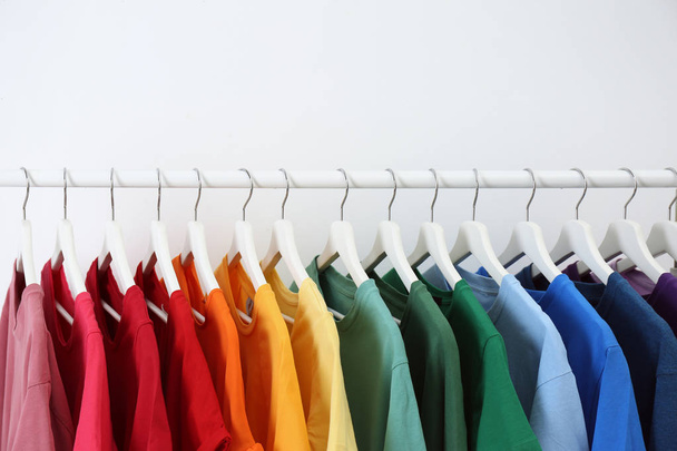Rack with bright clothes on white background. Rainbow colors - Fotoğraf, Görsel