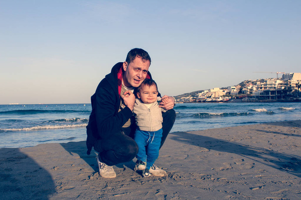 Papa et bébé garçon sur la plage de sable automne, visage expresion de famille heureuse
 - Photo, image