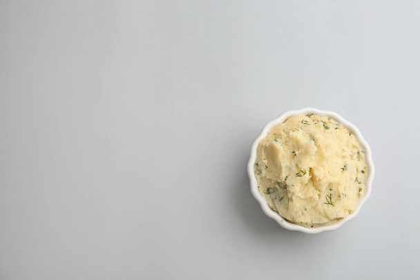 Bowl of tasty mashed potato on light background, top view with space for text - Фото, изображение