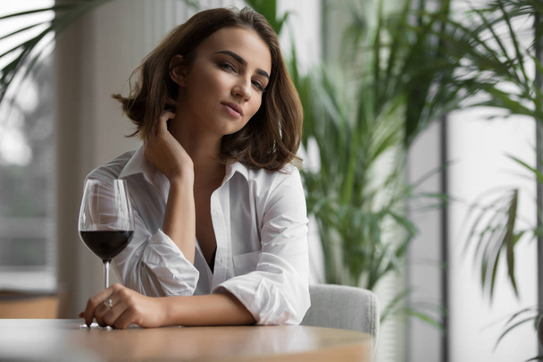 Young woman with a red wine glass sitting in the restaurant - Foto, immagini