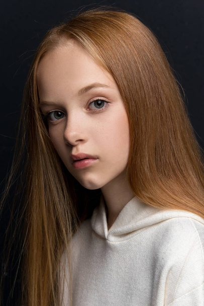 Close-up portrait of beautiful young redhead in studio on black background - 写真・画像