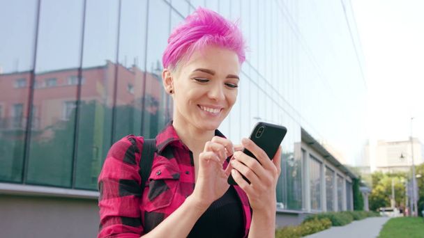 Kobieta z różowe krótkie włosy przy użyciu telefonu w mieście - Zdjęcie, obraz