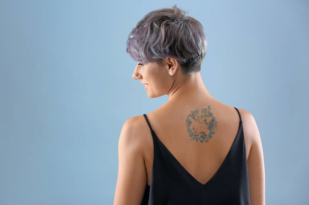 Young woman with tattoo on color background. Space for text - Foto, Imagen