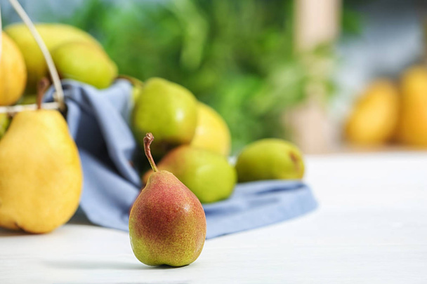 Fresh ripe pear on light table against blurred background - Valokuva, kuva
