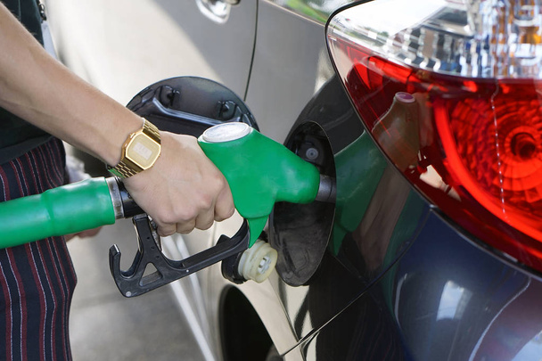 L'homme remplit l'essence dans sa voiture à une station-service à proximité. Un homme tenant une pompe à essence à une station
. - Photo, image