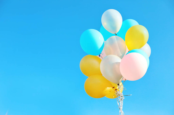 Bunch of colorful balloons against clear blue sky on sunny day. Space for text - 写真・画像