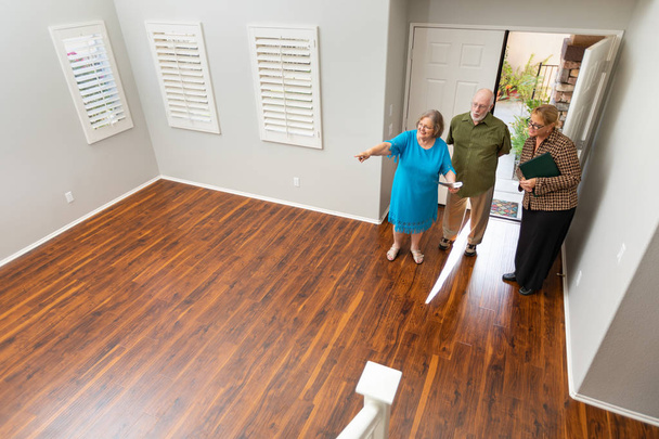 Agente inmobiliario femenino mostrando pareja adulta mayor un nuevo hogar
. - Foto, imagen
