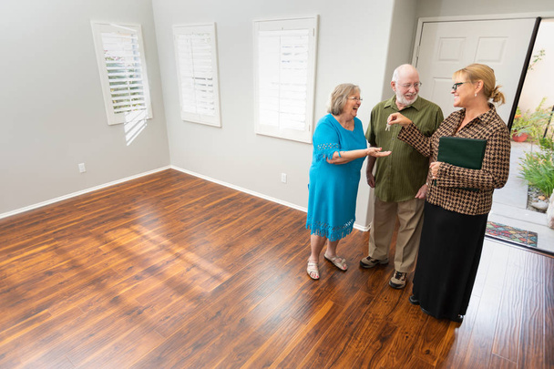 Senior felnőtt pár új haza új ház kulcsok átadása női ingatlanközvetítő. - Fotó, kép