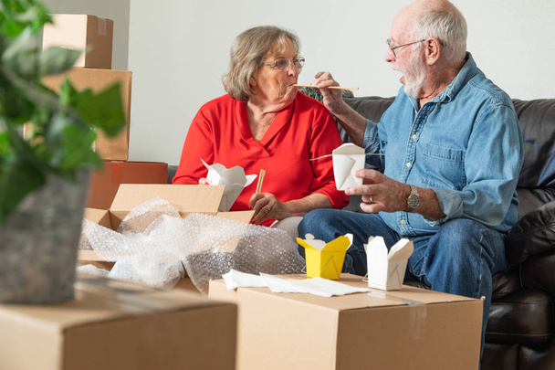 Senior Couple Enjoying Chinese Food Surrounded By Moving Boxes. - Photo, Image