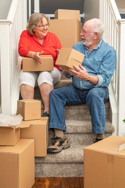 Senior Couple Resting On Stairs Surrounded By Moving Boxes. - Photo, Image
