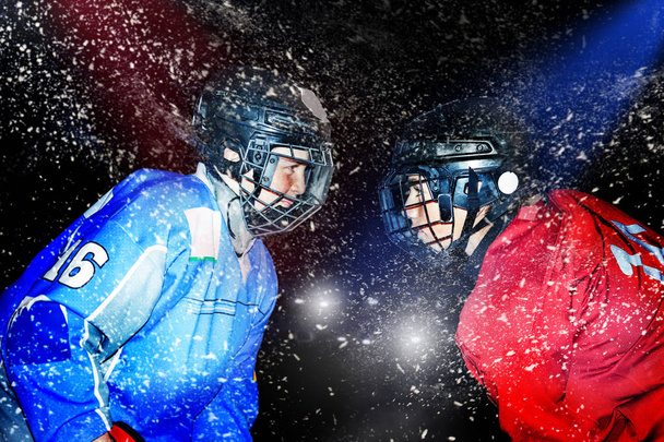 Close up portrait of two teenage boys, ice hockey players, standing face-to-face, floodlighted over dark background - Zdjęcie, obraz