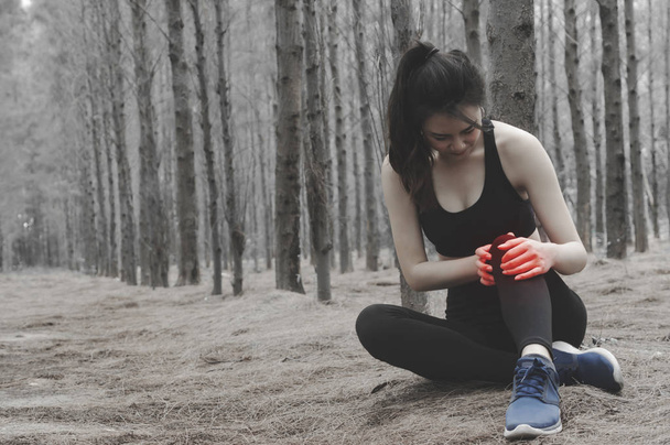 Unhappy young woman sitting in the garden, grabbing an ankle, unable to start running because of sport injury, feeling pain. Beginner doing wrong exercise. - Photo, Image