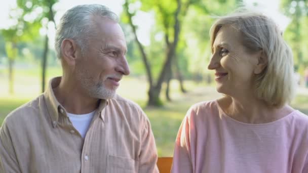 glückliches altes Paar blickt in die Kamera, umarmt, lächelt zufrieden mit dem Leben - Filmmaterial, Video