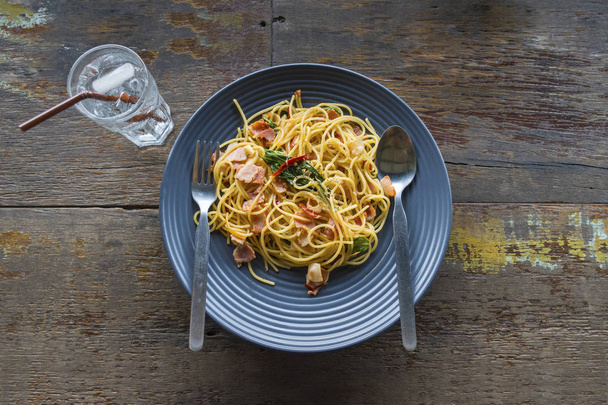 Eski ahşap tahta üzerinde plaka üzerinde pastırmalı kızarmış spagetti. İtalyan mutfağı. - Fotoğraf, Görsel