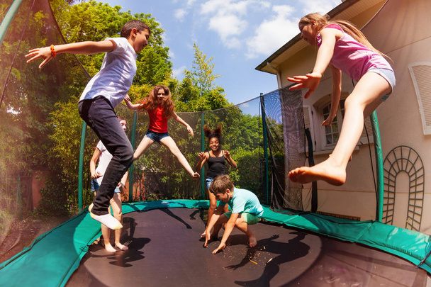 Portrait of happy friends, multiethnic boys and girls, jumping on the backyard trampoline in summer - Fotografie, Obrázek