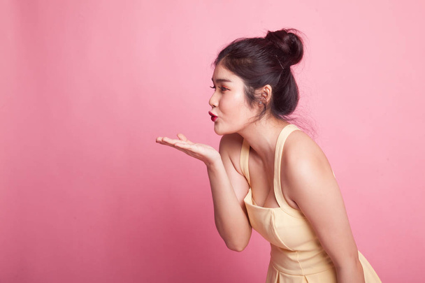 Beautiful young Asian woman blow a kiss on pink background - Foto, imagen
