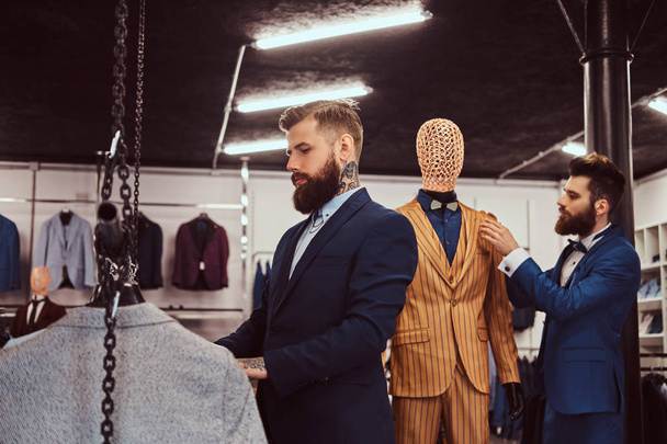 Deux assistants de magasin élégants élégamment habillés travaillant dans un magasin de vêtements pour hommes
. - Photo, image