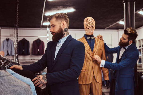 Два стильных продавца элегантно одеты, работая в магазине мужской одежды
. - Фото, изображение