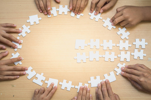 Hände von verschiedenen Leuten, die Puzzle zusammenbauen, Jugendteam setzt Teile zusammen, um das richtige Spiel zu finden, Unterstützung bei der Teamarbeit, um ein gemeinsames Lösungskonzept zu finden, Nahsicht von oben - Foto, Bild