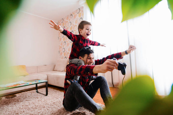 joyeux père excité et petit fils en chemises rouges jeu de console avec des manettes
 - Photo, image