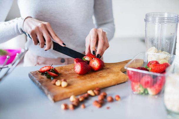 mujer cortando fresas frescas en el mostrador de cocina
 - Foto, imagen