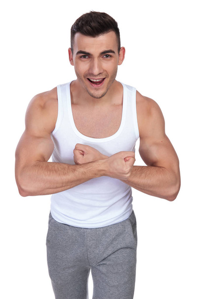 portrait of excited man in undershirt flexing his hands while standing on white background - Foto, Imagen