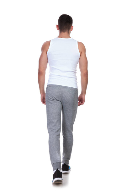 vista trasera del hombre joven en forma de camiseta pisando fondo blanco, imagen de longitud completa
 - Foto, imagen