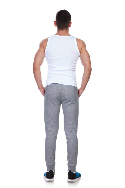 rear view of fitness man standing on white background with hands in pockets, full body picture - Valokuva, kuva