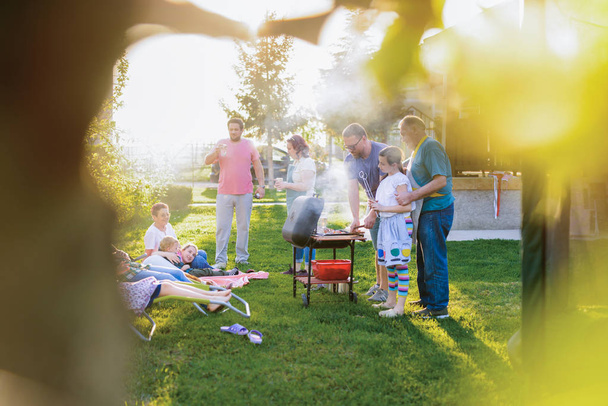 alegre cocina familiar con parrilla al aire libre en el patio trasero en el día soleado - Foto, Imagen