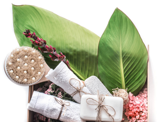 productos de spa orgánicos en una caja de madera sobre un fondo blanco con hojas tropicales, un concepto de cuidado corporal y relajación
 - Foto, Imagen