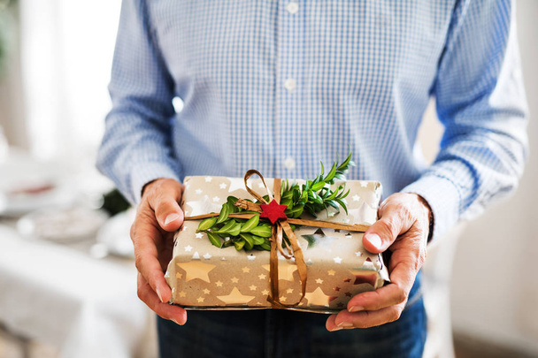 An unrecognizable senior man holding wrapped present at Christmas time. - Valokuva, kuva