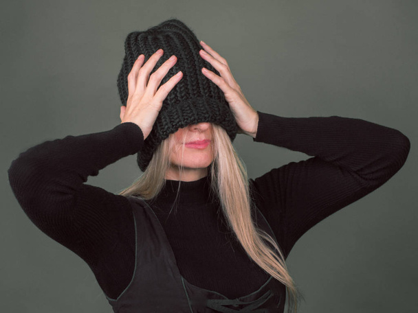 Jonge vrouw in grote gebreide muts hoed gesloten haar gezicht. - Foto, afbeelding