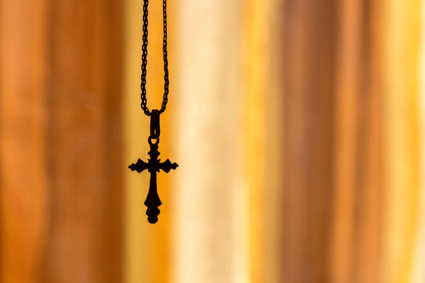 cross on a chain on an orange background - Fotó, kép