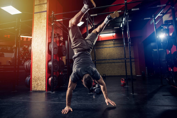 Homme sportif vital fort debout sur ses mains dans la salle de gym
. - Photo, image