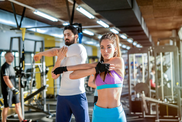 Ισχυρή ταιριάζουν νεαρό ζευγάρι τεντώνοντας τους μυς μετά την προπόνηση στο γυμναστήριο. - Φωτογραφία, εικόνα