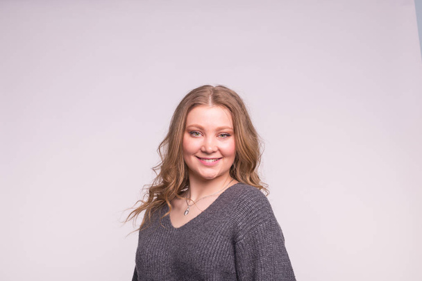 Young blonde woman wearing grey wool sweater on white background - Photo, Image