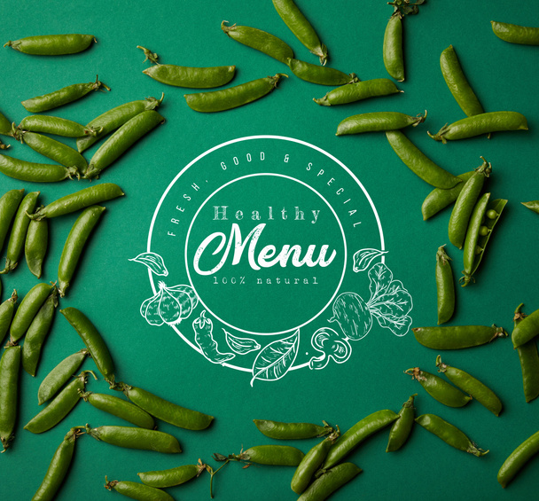 top view of round frame made of pea pods on green surface with "healthy menu" lettering - Photo, Image