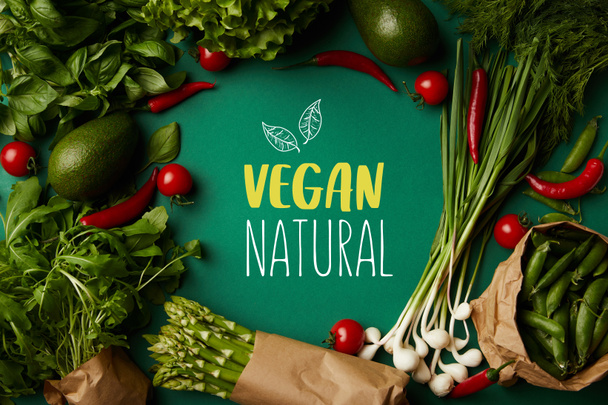vista superior de marco redondo hecho de varias verduras maduras en la superficie verde con letras "veganas naturales"
 - Foto, Imagen