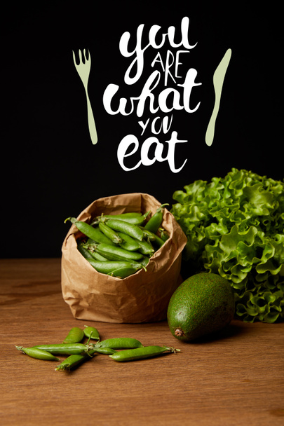 close-up shot of avocado, green peas and lettuce on wooden surface with "you are what you eat" inspiration - Foto, imagen