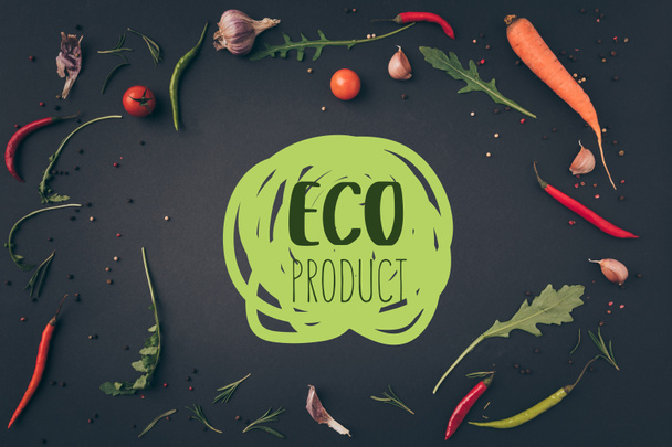 top view of arugula, carrot and chili peppers on gray surface with "eco product" lettering - Fotografie, Obrázek