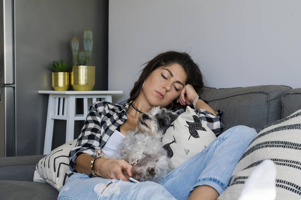 Sleeping girl with dog on sofa at home - Foto, imagen