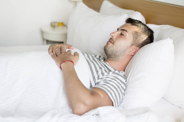 Handsome young man happily sleeping in white bed - Foto, Bild
