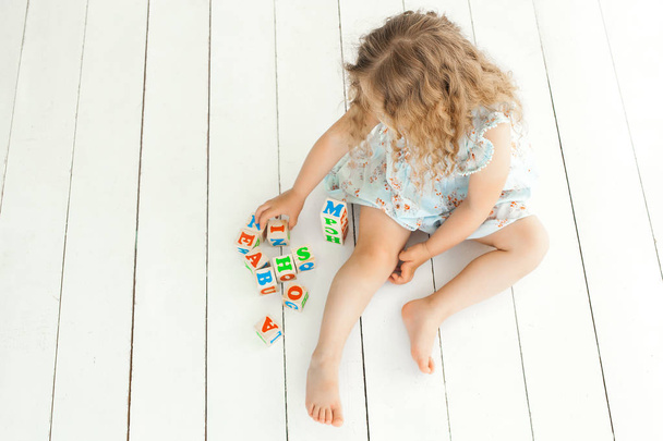 Schattig klein meisje speelt met abc kubussen  - Foto, afbeelding