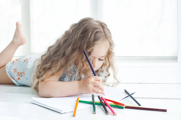 Милая маленькая девочка рисует картину дома
 - Фото, изображение