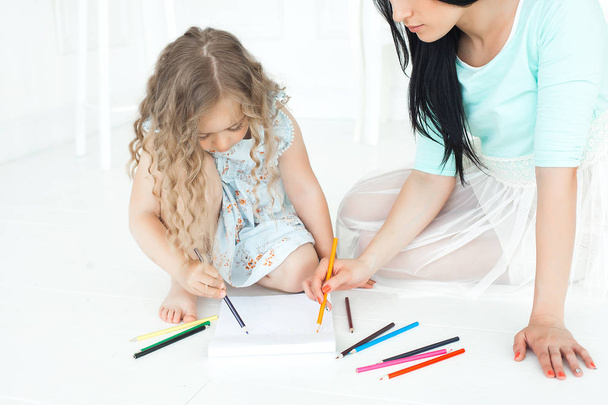 Cute little girl and her mother drawing a picture together - Фото, зображення