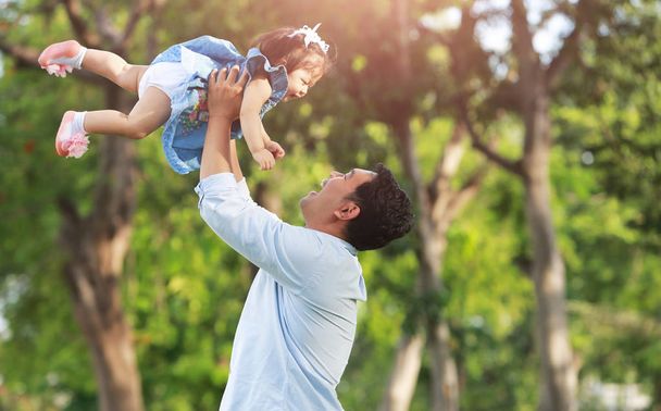 Vader overgeven dochter in de lucht op het park. - Foto, afbeelding