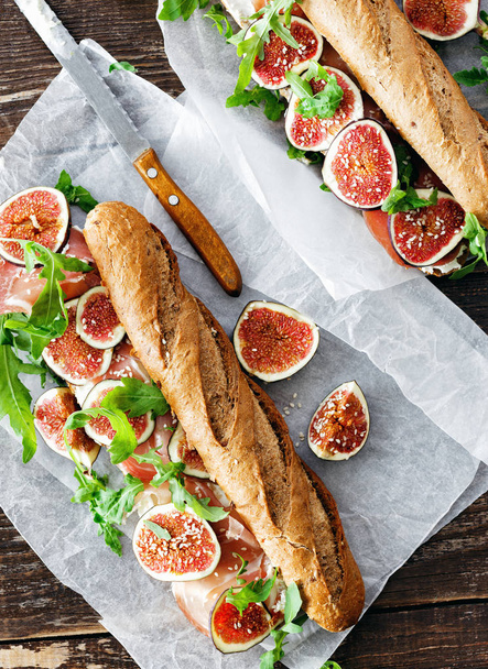 Sandwich with prosciutto, mascarpone cheese and figs with glass of white wine on dark background top view - Foto, immagini