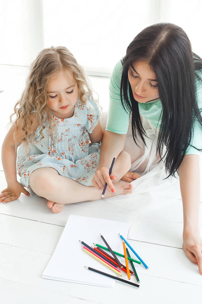 Menina bonito e sua mãe desenhando um quadro juntos dentro de casa
.  - Foto, Imagem
