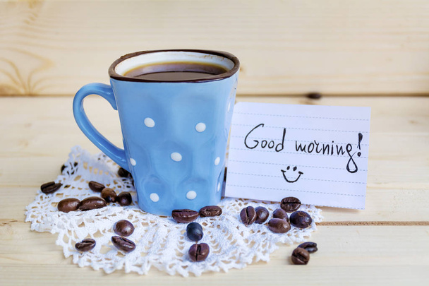 blue coffee mug with white dots and note good morning on a wooden background - Foto, imagen