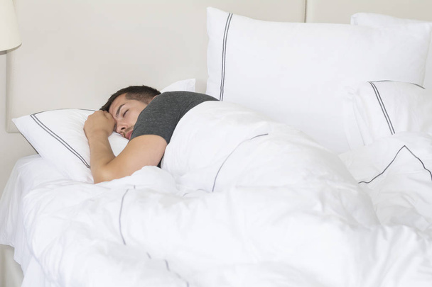 Handsome young man happily sleeping in white bed - Fotografie, Obrázek